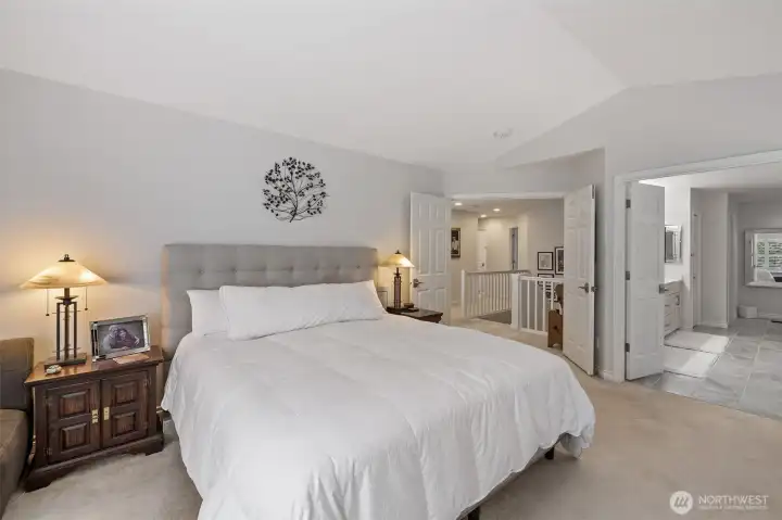 Looking toward the hallway and the ensuite bathroom, the primary bedroom feels open and inviting. This view highlights easy access to the luxurious ensuite, reinforcing the suite’s perfect combination of comfort, functionality, and sophisticated design.