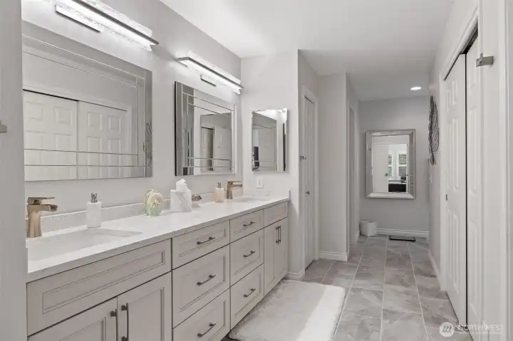 The primary suite’s bathroom is a luxurious retreat, designed with both elegance and functionality in mind. Dual sinks provide ample space for daily routines, while a freestanding soaking tub invites relaxation and indulgence. A large, glass-enclosed shower adds a modern touch, complementing the sophisticated finishes and serene ambiance. Every detail has been thoughtfully curated to create a spa-like experience within the comfort of home.