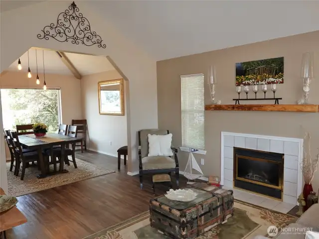 Living Room w/ vinyl plank flooring, propane fireplace insert, and leading into the Dining Room.
