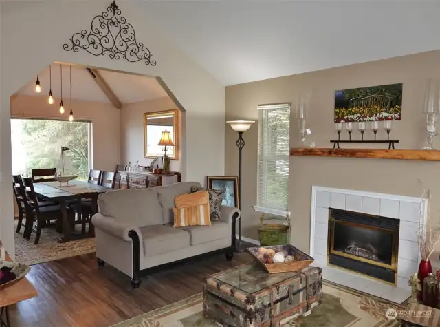 Living Room w/ vinyl plank flooring, propane fireplace insert, and leading into the Dining Room.