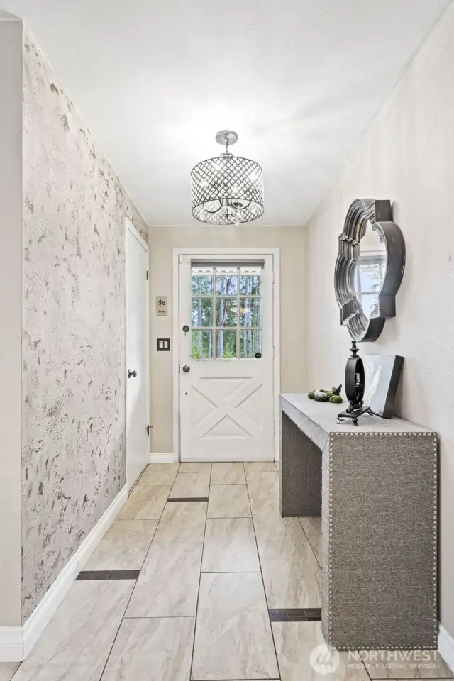 Inside, the entryway enjoys this cute front door, fun light fixture, and ceramic tile flooring.