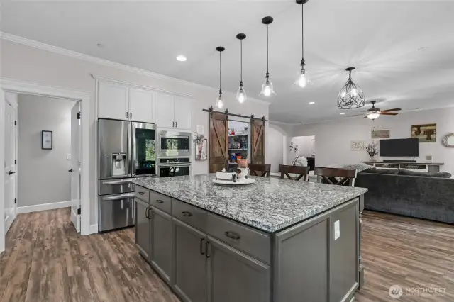 Chef's kitchen with large center island, stainless appliances and granite countertops.