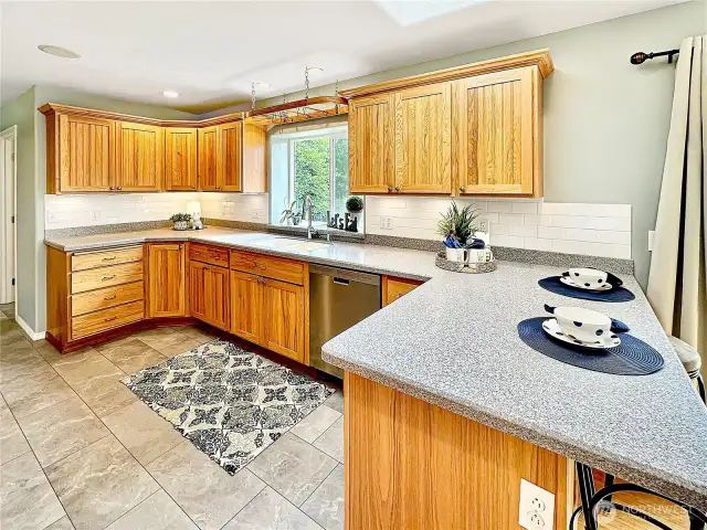 Beautiful kitchen with loads of hickory cabinets, solid surface counters, eating space with skylight above and breathtaking view of the rear yard from the kitchen window.