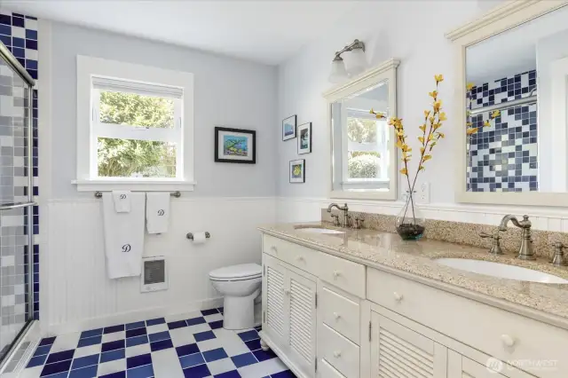 Next to the Guest Suite is a spacious 3/4 bath with hickory cabinets, dual sink vanity with quartz countertops, beadboard walls and multi-colored ceramic tile flooring & shower surround.