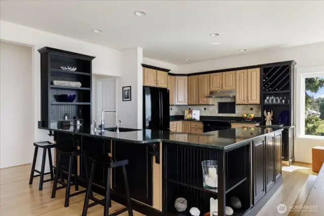 Cook's Kitchen in the Open Floor Plan with Hickory cabinets & flooring, Quart countertops & Tile surround, Black appliances, and eating area.