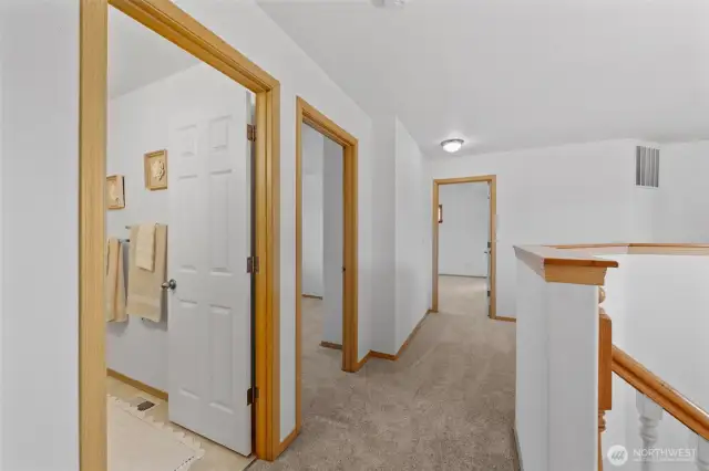 Looking to your left another view of the full bathroom, the 3rd guest bedroom on the left and the primary with en-suite straight ahead.