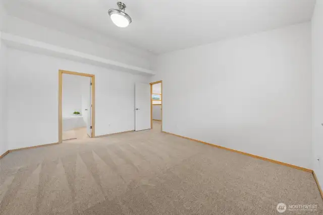The primary bedroom easily fits a king side bed and has tall ceilings with a plant or picture ledge.  Middle open door is to your en-suite.