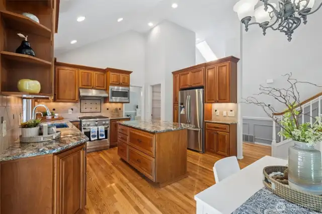 Here's the Gourmet Kitchen with cherry cabinets, slab granite, stainless appliances, tiled backsplash and an island with seating.