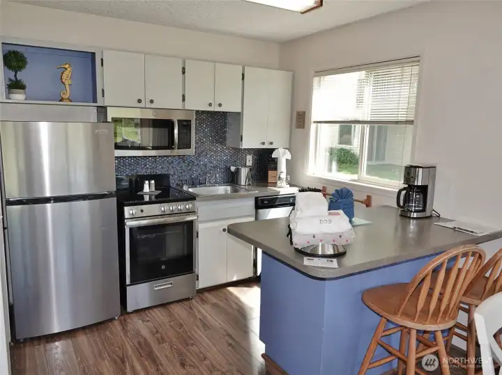 Fully-equipped Kitchen w/ Stainless Steel appliances, Eating Bar, and kitchenware.