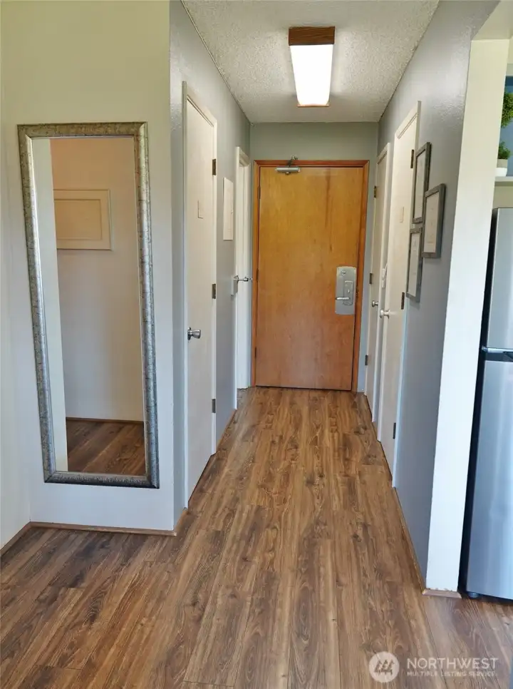 Entry. Laminate flooring.   (The 1st 2 Doors on the left and right are the owner's locked closets. Far right door is the coat closet. Far left door is the 1/2-bathroom.)