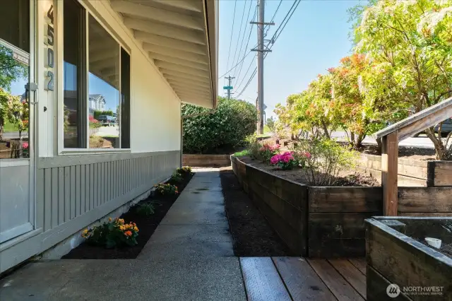 Covered walkway with colorful plants create a welcoming approach