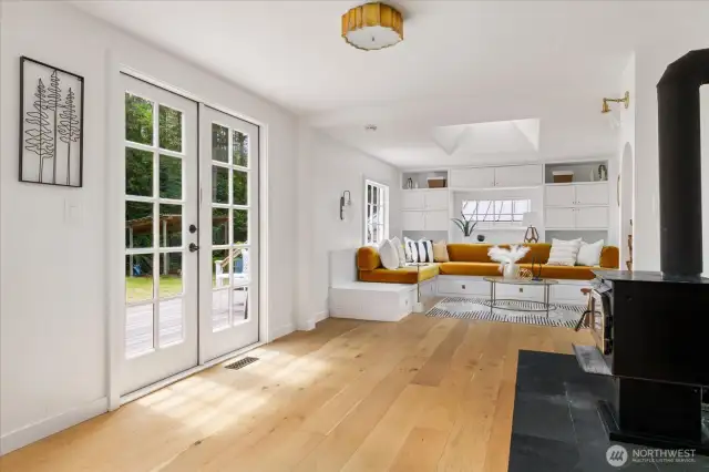 Living room and wood stove with french doors leading to an expansive deck