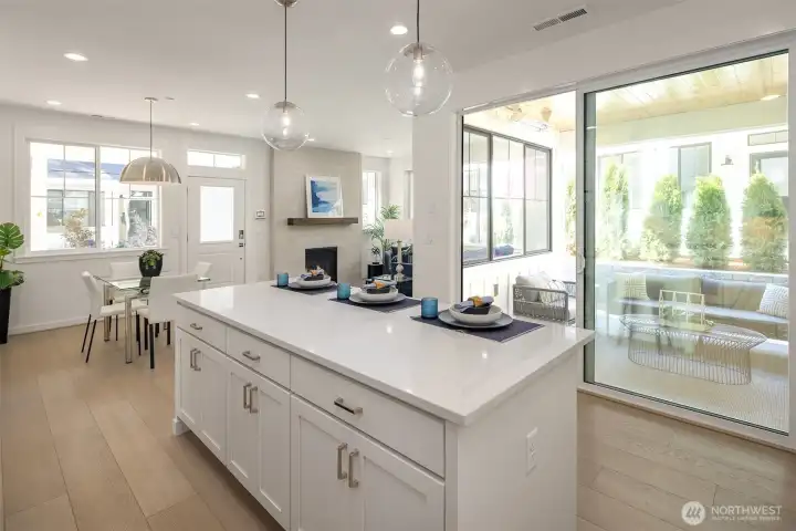 Island free of sink or stove offers plenty of space for dining or working. Extra large slider opens to covered patio.  Photos of a staged Marigold home. Surfaces and finishes will vary from subject home.