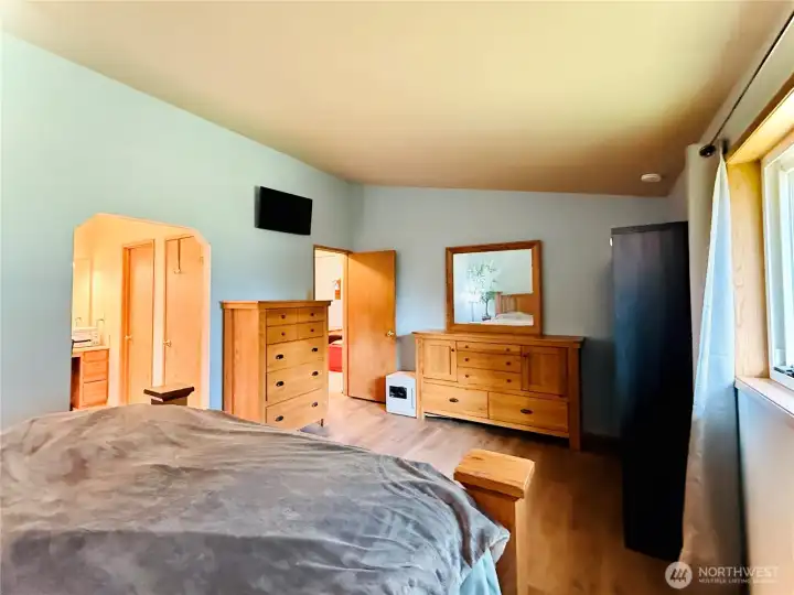 Primary suite view from the entryway, vaulted ceiling, LVP, spacious layout, dual closets and 3/4 bathroom ensuite with makeup counter