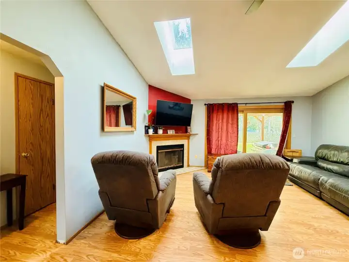 Living room with LVP, vaulted ceilings, skylights for natural light, hallway to left access front and back bedrooms with full bathroom separating them