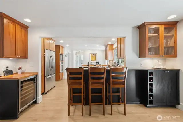 Between the kitchen and the family room is the breakfast bar, work desk and plenty of wine storage! -- Installed wine fridge stays.