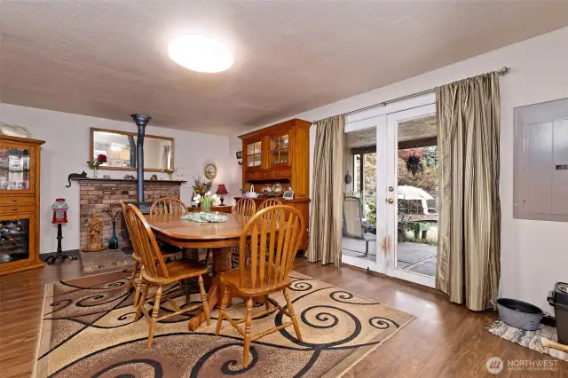 The dining room with a free-standing pellet stove, and French doors leading to the fully-fenced back yard and the enclosed hot tub room.