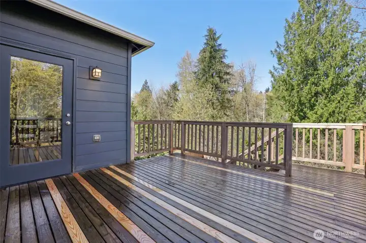 Deck just off the kitchen and living room with stairs that lead to the backyard patio and firepit