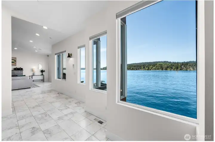 As you make your way up to the second level, expansive windows immediately draw your attention to panoramic waterfront views that follow you into the living spaces beyond. Marble tile flooring, soaring ceilings, and natural light create a memorable introduction to the main living area.