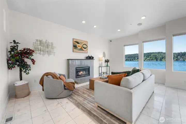 Gather in the living room where vaulted ceilings, a fireplace centerpiece, and expansive waterfront views create a space designed for both relaxing and entertaining. Walls of windows bring the outdoors in while creating ever-changing scenery throughout the day.