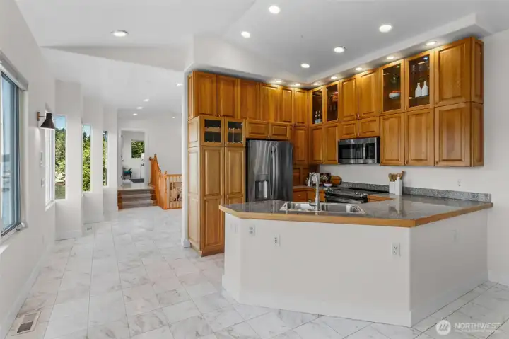 The kitchen combines functionality and style with raised-panel cabinetry, glass-front display cabinets that add architectural interest, granite countertops, and an oversized peninsula designed for gathering and everyday living. Positioned at the heart of the second level, this space keeps waterfront views and entertaining spaces close at hand.