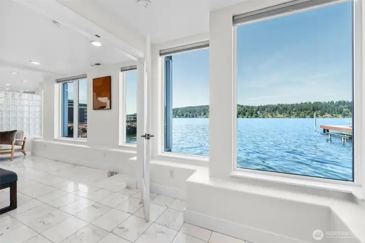Step into the Primary Suite where marble tile flooring, walls of windows, and panoramic waterfront views immediately set the tone. This expansive retreat offers an open layout designed to maximize both space and the connection to the water beyond.