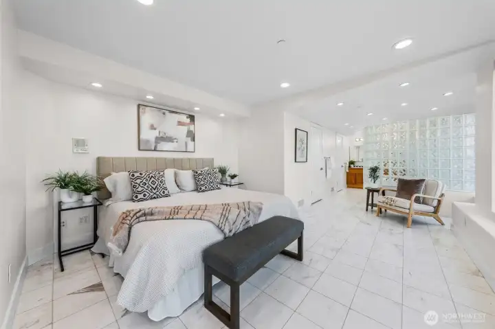 Wake each morning to panoramic waterfront views from this expansive Primary Suite, where walls of windows create an ever-changing backdrop. The open layout flows seamlessly toward the spa-inspired bath, creating a true private retreat.