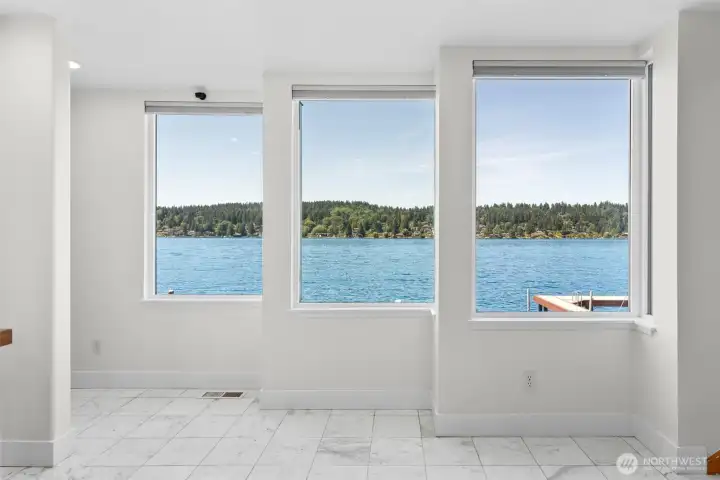 Step into an entry that makes an immediate impression with marble tile flooring, clean modern lines, and expansive windows framing stunning water views. This welcoming space sets the tone from the moment you arrive, blending style, light, and a connection to the waterfront beyond.
