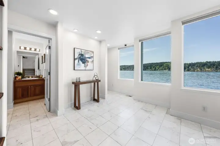 An entry designed to impress with marble tile flooring, expansive waterfront views, and bright open spaces that immediately draw your eye to the water. On this level, you'll find the main-level bedroom, 3/4 bathroom, laundry room, and convenient access to the garage—creating a layout built for everyday ease.