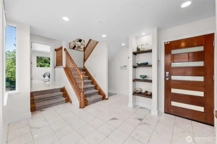 This central entry connects all three levels of the home, creating easy flow throughout the layout. Head upstairs to the second level featuring the kitchen, living room, and additional bedroom, while the main level offers a bedroom just up the split staircase and the lower level leads to the primary suite and another bedroom.