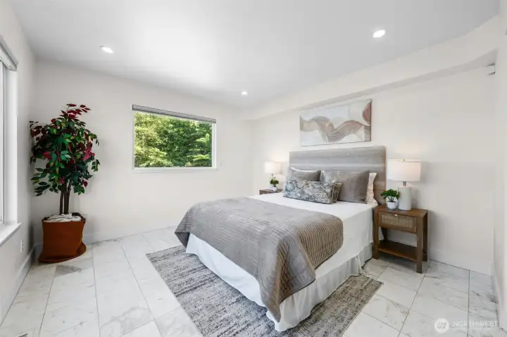 Located on the main level this bedroom offers a spacious layout with marble tile flooring, recessed lighting, and a peaceful setting for guests or everyday living. Large windows bring in natural light while maintaining a bright and inviting atmosphere.