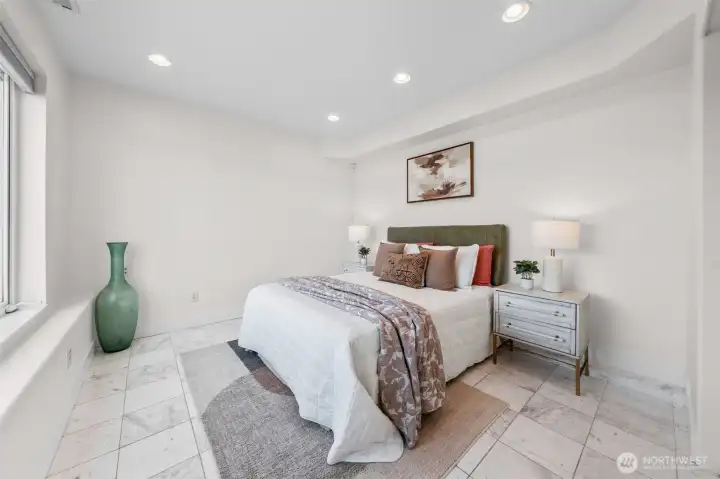 Lower level bedroom offers a spacious layout with marble tile flooring, recessed lighting, and plenty of room to create a comfortable retreat for guests or everyday living. Clean lines and a neutral palette create a space ready for your personal touch.
