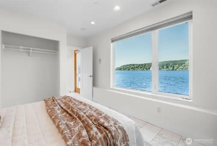 Wake up to waterfront views right from the lower level bedroom, where oversized windows frame the water and bring natural beauty indoors. This room combines peaceful scenery, creating a connection to the waterfront lifestyle.