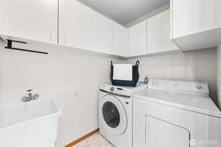 The main level utility room is designed for convenience with upper storage cabinetry, a utility sink, and dedicated laundry space. Functional and organized, this space keeps everyday essentials tucked away while maximizing storage and efficiency.
