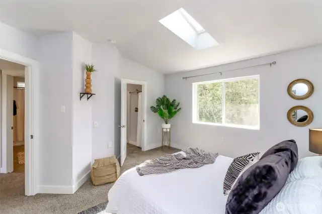 This view of the primary suite highlights the large window that frames the tranquil backyard and the serene protected green space beyond.