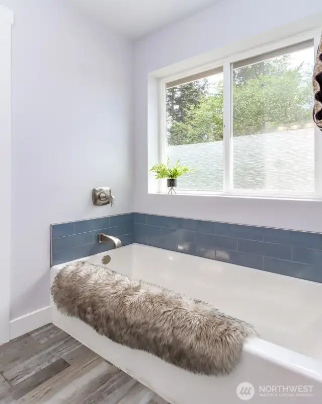 Enjoy the relaxing soaking tub, perfectly positioned beneath a privacy-glass window to create a discreet and tranquil retreat within the primary bathroom.