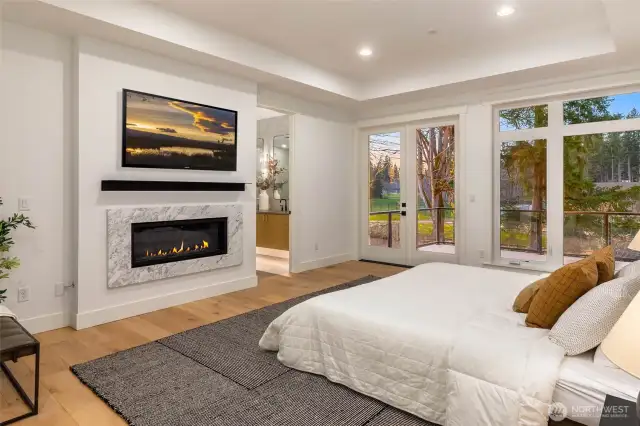 Dramatic Primary bedroom accessed throguh double doors and highlighted by custom fireplace detail and deck