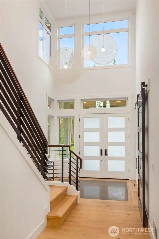 Sprawling and light drenched 2 story entry accentuated by stunning custom tile floor detail and dramatic contemporary hanging light fixtures