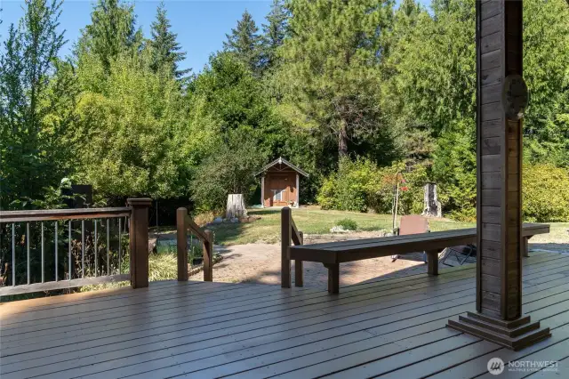 View from sliding doors to covered porch, deck, and keystone patio. Pumphouse seen straight ahead. Lower shop is to the left.
