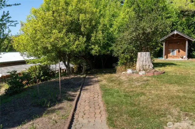 View from keystone patio. Pumphouse on right. Pear and apple trees at end of path. Large "tractor barn" below with additional garage space, large carport, and storage room.