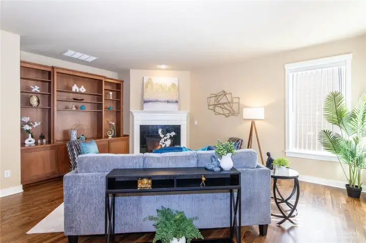 Living room with built-in shelving, fireplace and dining space.