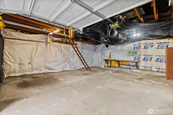 Large 2 car garage with insulation, and ladder leading to overhead storage possibilities.