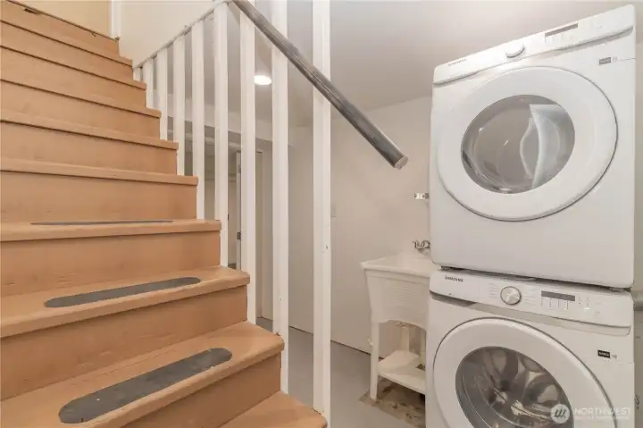 Stairs to basement with laundry and utility sink