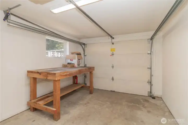 Unfinished shop space with rolling garage door for all your lawn storage, green thumb projects or crafting needs