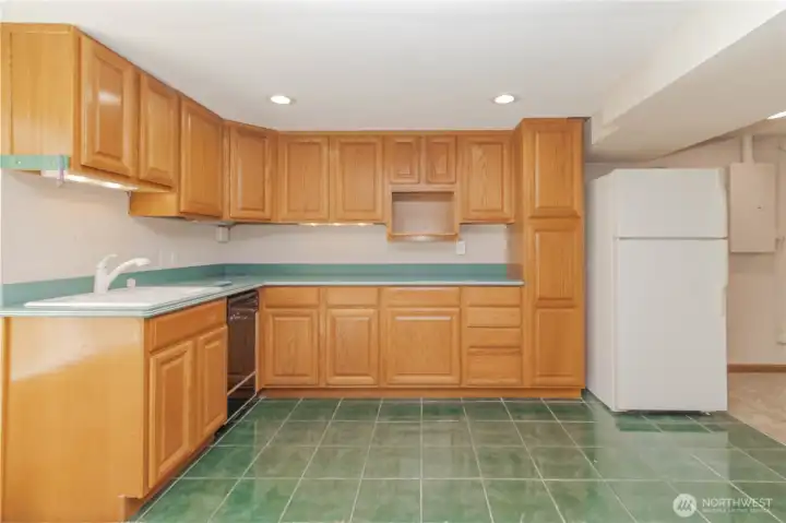 Basement kitchen area has tile flooring, sink, dishwasher and fridge, no heating element