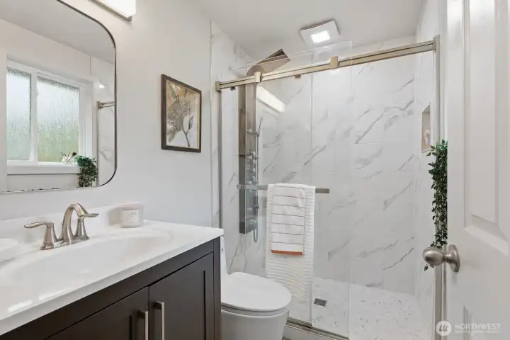 Fully remodeled ¾ ensuite bath featuring tile flooring, updated shower, modern lighting, a stylish vanity, and upgraded fixtures.