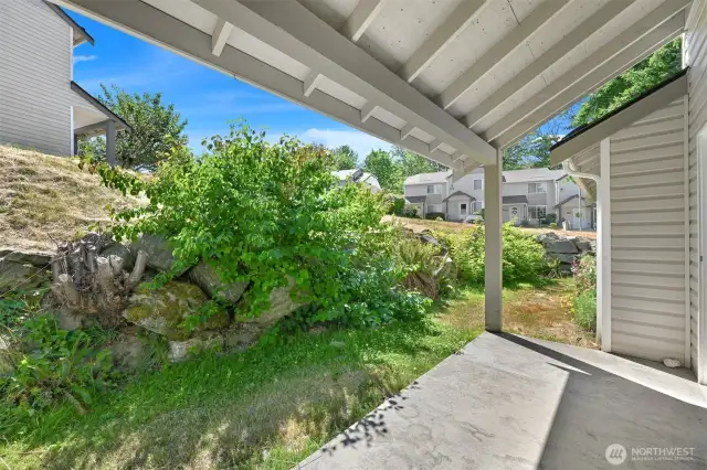 The roof over the patio and the rock wall add to a nice cozy outdoor space