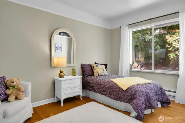 Serene main floor bedroom with backyard outlook,original trim, picture rail, new paint & lighting.