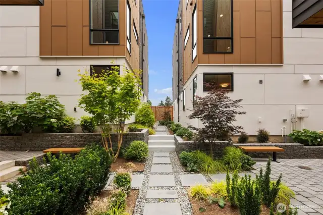 Tucked between these homes, beautifully landscaped gated courtyards create a serene community feel.  Paver walkways meander through lush plantings, mature maple trees, and blooming hydrangeas.  Benches offer quiet spots to relax or gather with neighbors. A rare blend of nature and neighborhood in the heart of the city.