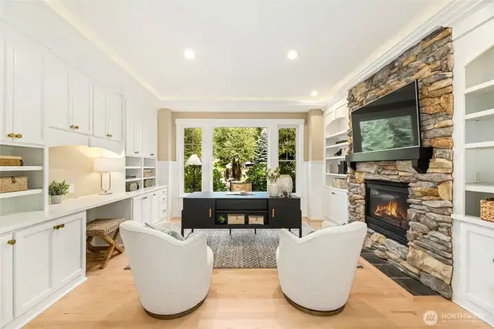 Luxury office retreat w/ designer built-ins, statement stone fireplace, & front yard views.